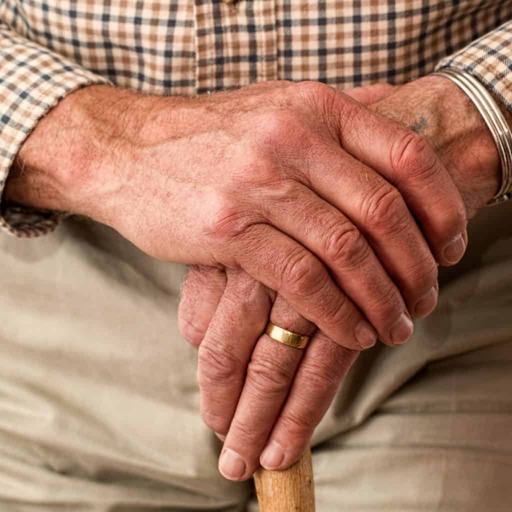 Elderly man clasping hands with ring on finger