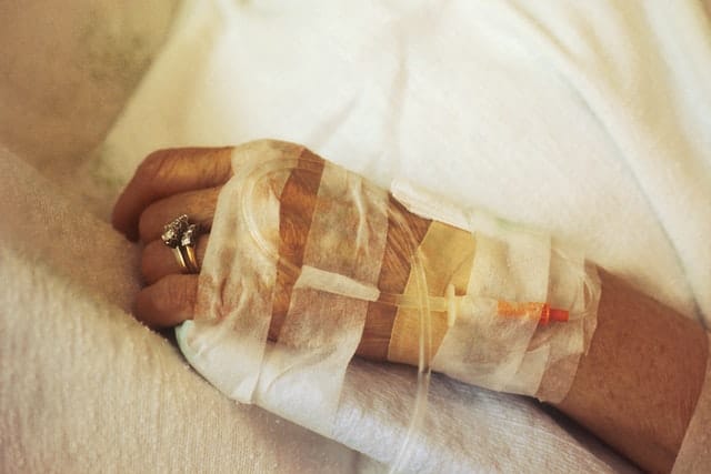 Woman in hospital with IV in arm wearing a wedding band.