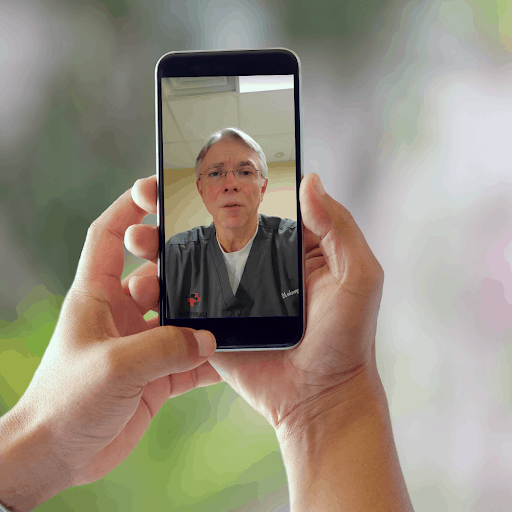 Hands holding smartphone with Dr. Roger Moczygemba on screen