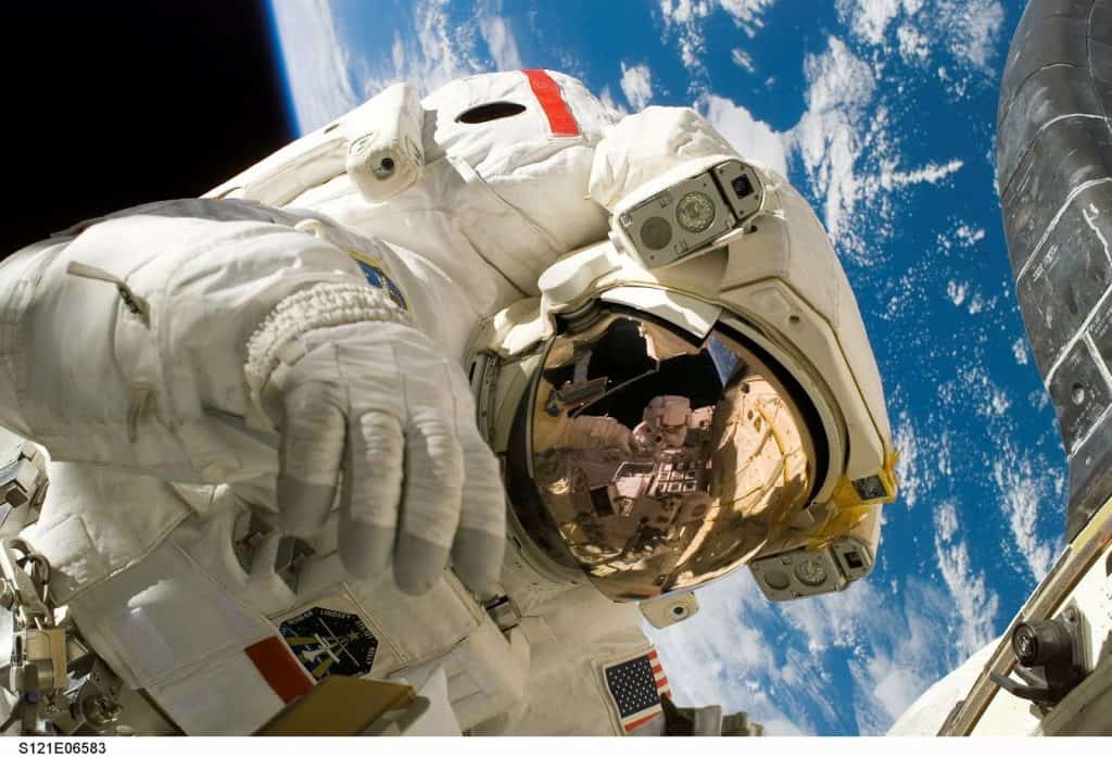 NASA astronaut floating in outer space above the earth in orbit in a space suit.