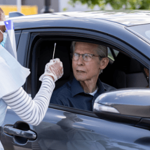 Elderly man taking an antigen test from inside his car